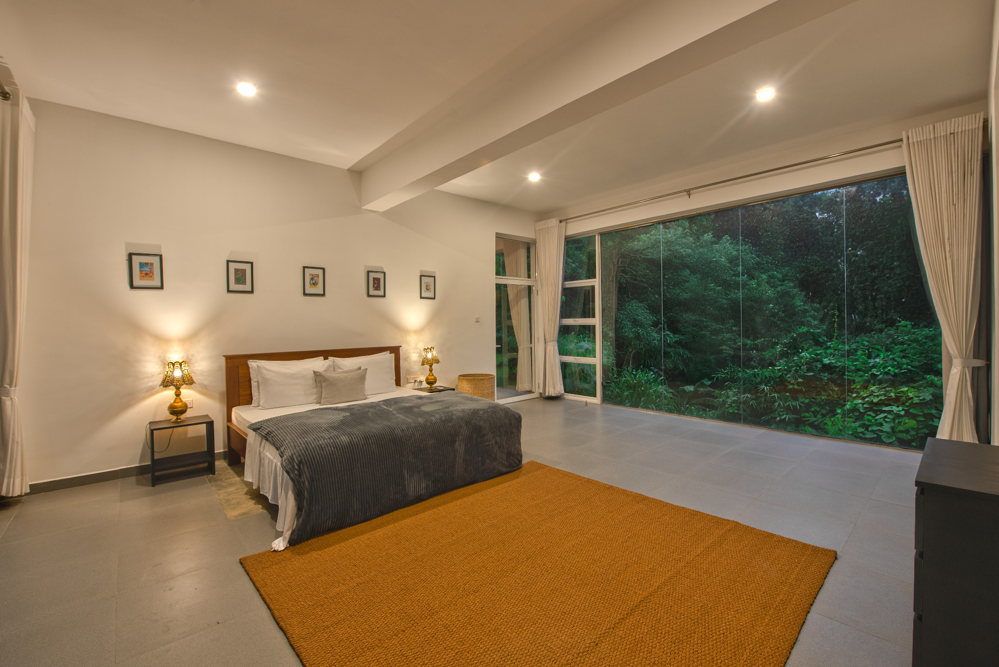 Bedroom with large glass window overlooking greenery